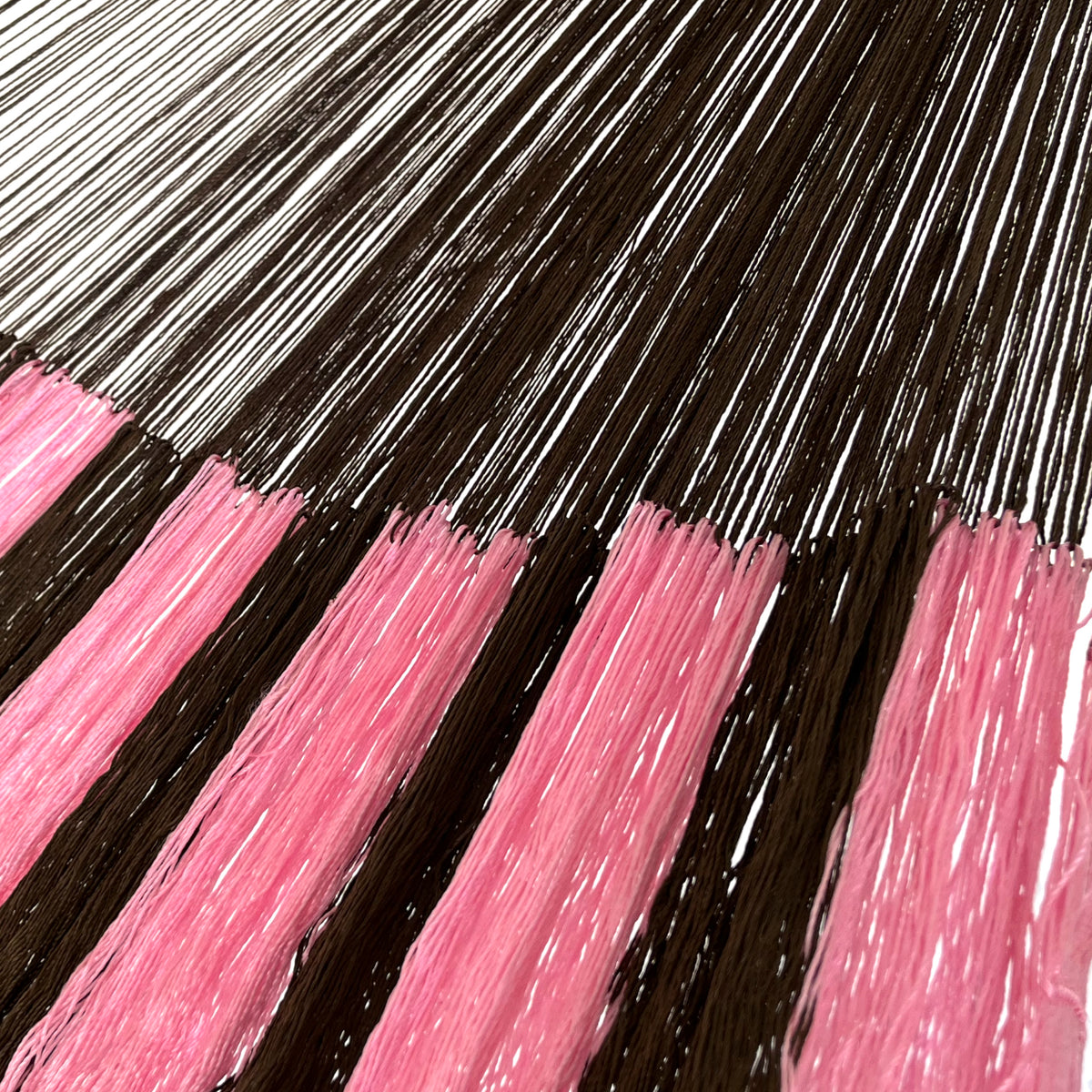 Detalle de la unión entre el cuerpo y el brazo de una hamaca yucateca artesanal de nylon suave rosa y café