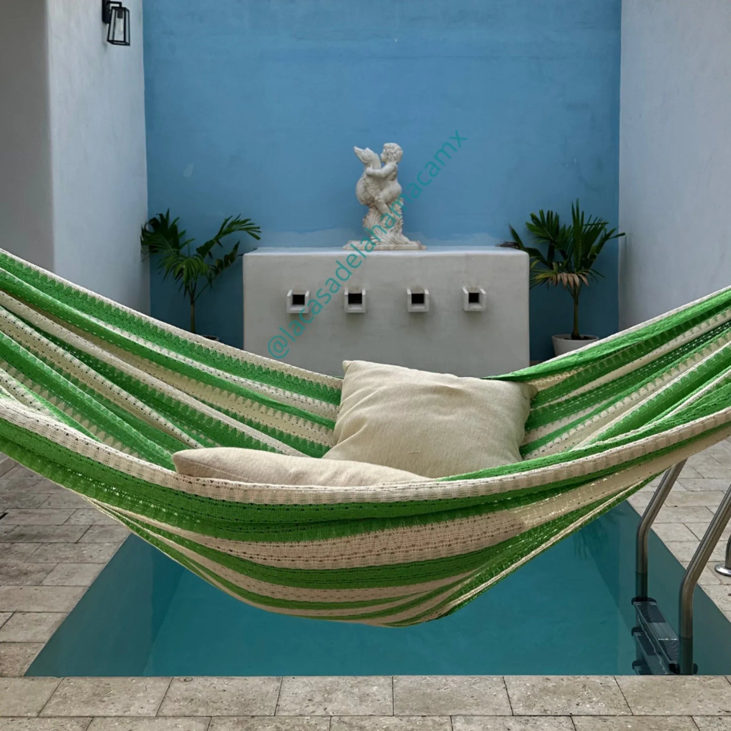 Hamaca verde grande de algodón colocada en terraza de casa junto a alberca
