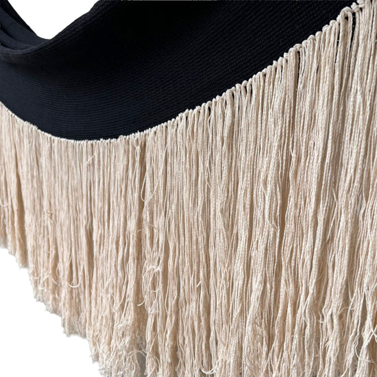 Primer plano de los flecos largos color beige en el borde de una hamaca mexicana de algodón negro