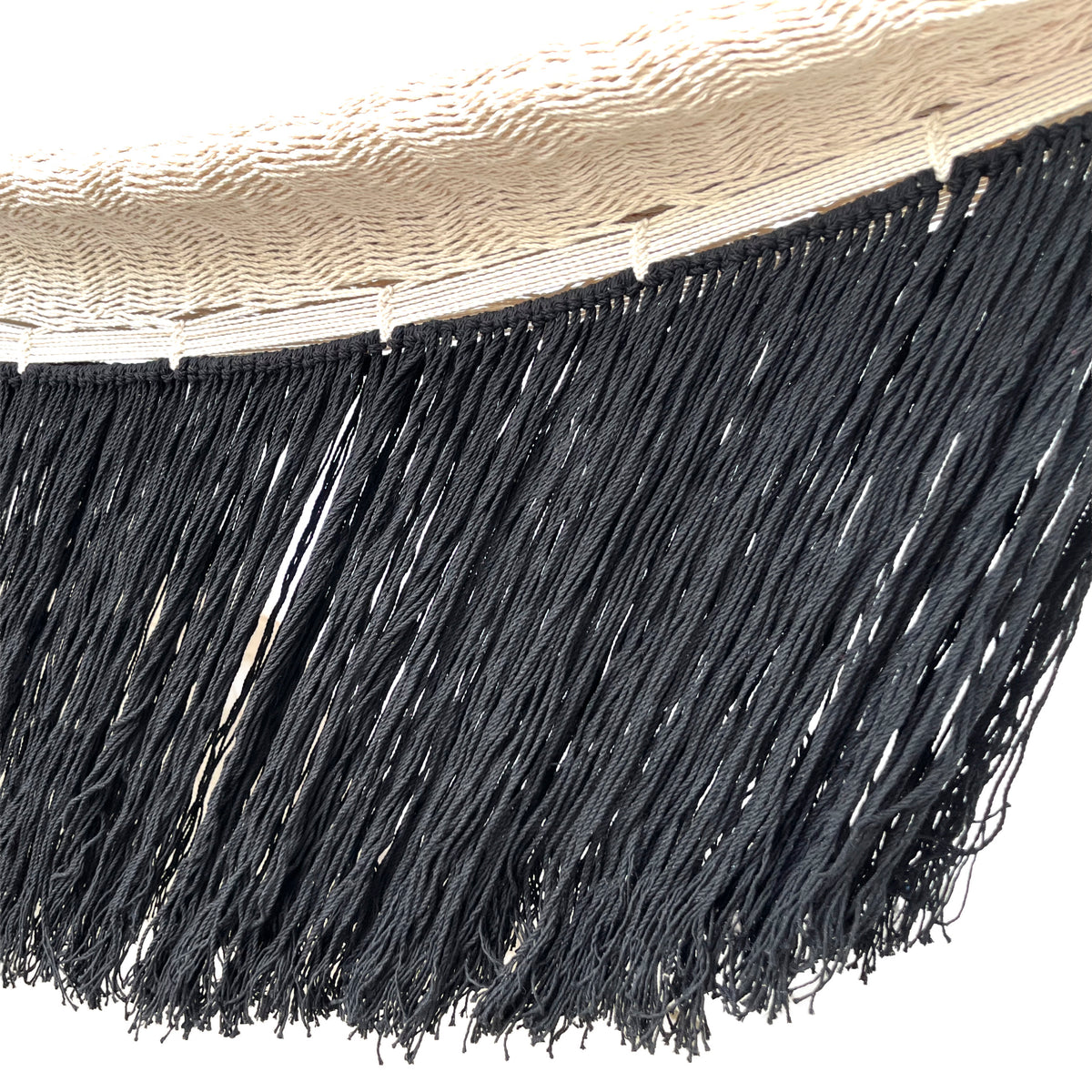 Primer plano de los flecos largos negros en el borde de una hamaca yucateca artesanal de algodón beige
