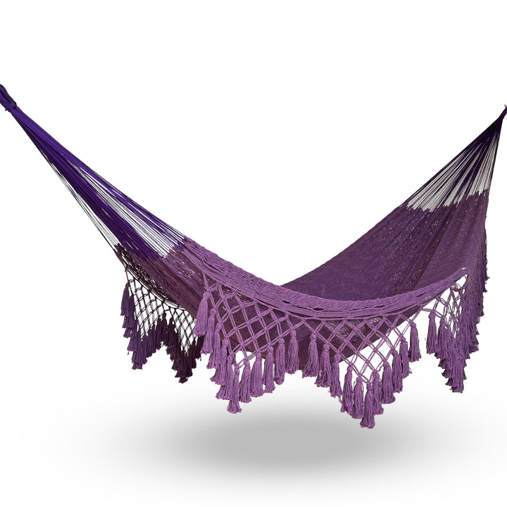 Hamaca yucateca artesanal de algodón morado con macramé colgada y abierta sobre fondo blanco