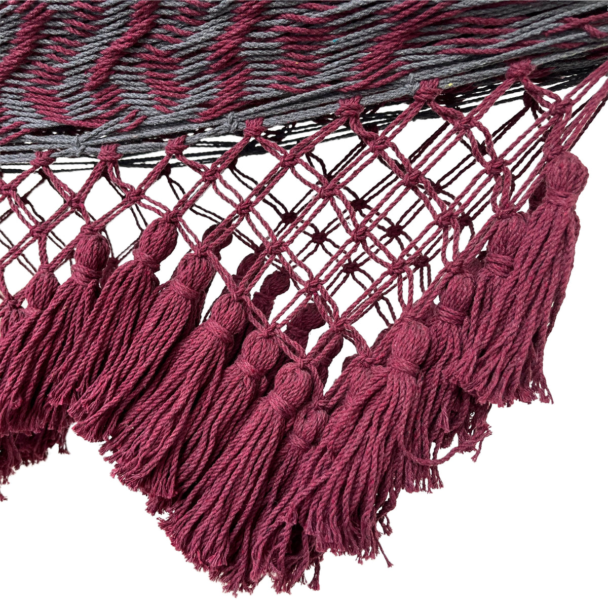 Primer plano del macramé tejido a mano con flecos decorativos de una hamaca yucateca artesanal de algodón rojo y gris