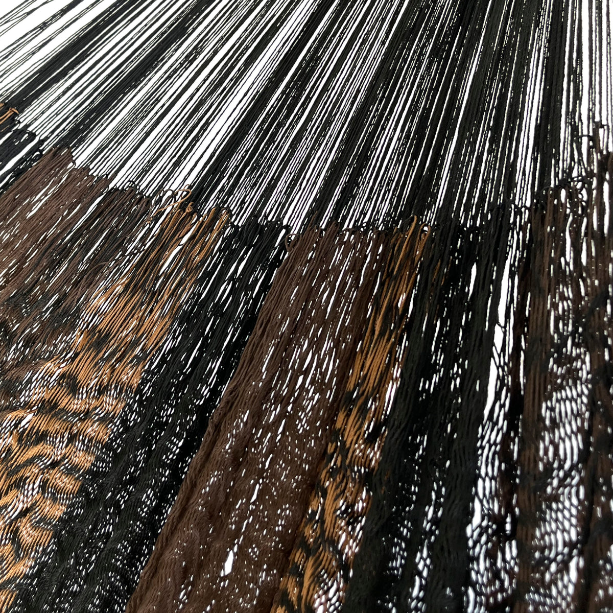 Detalle de la unión entre el cuerpo y el brazo de una hamaca yucateca artesanal de nylon suave café y negro