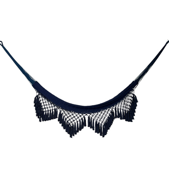 Hamaca yucateca artesanal de algodón azul vista de frente, con tejido suspendido, bordes de macramé y flecos decorativos.