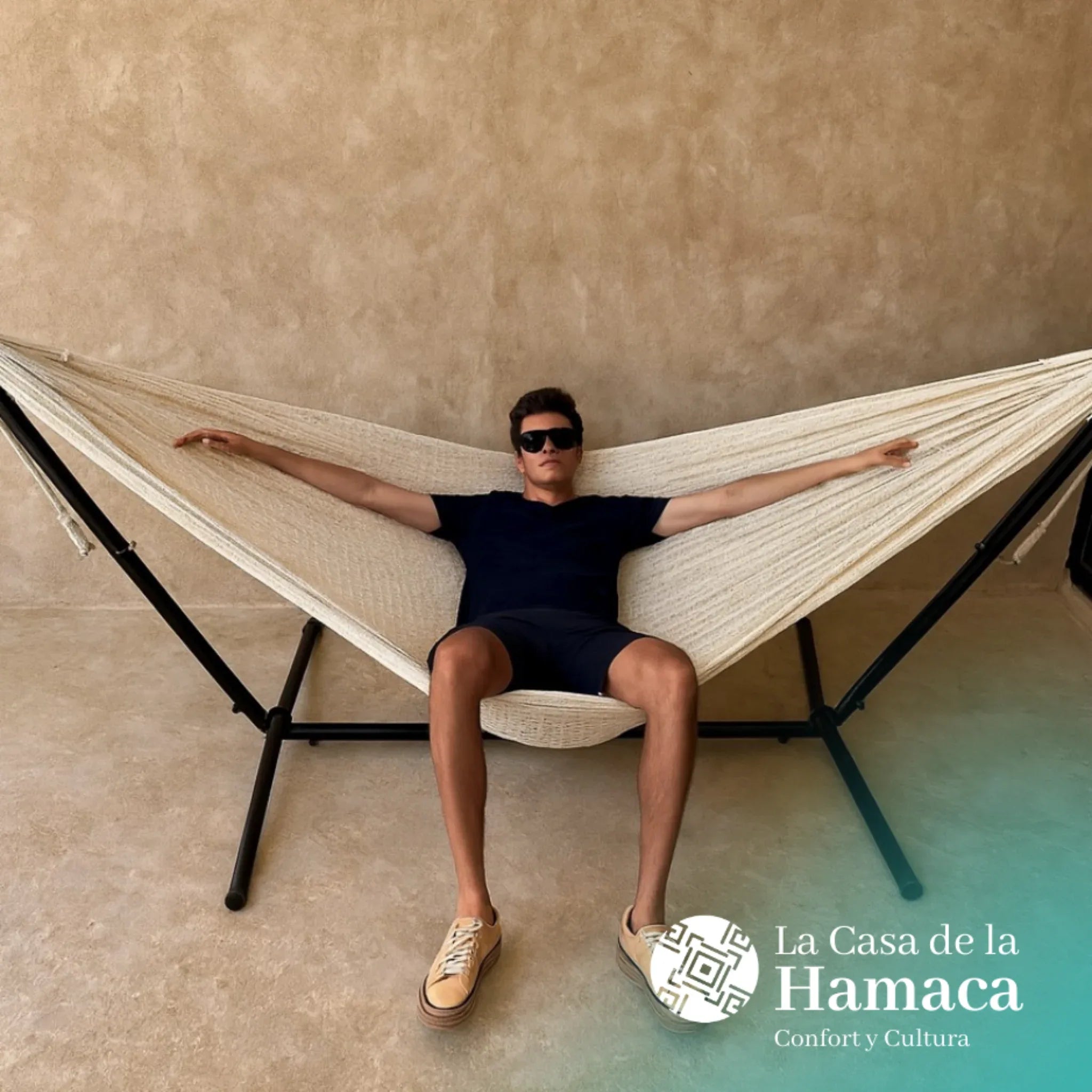 Hamaca mexicana beige de algodón colocada en base, con un hombre descansando sobre ella