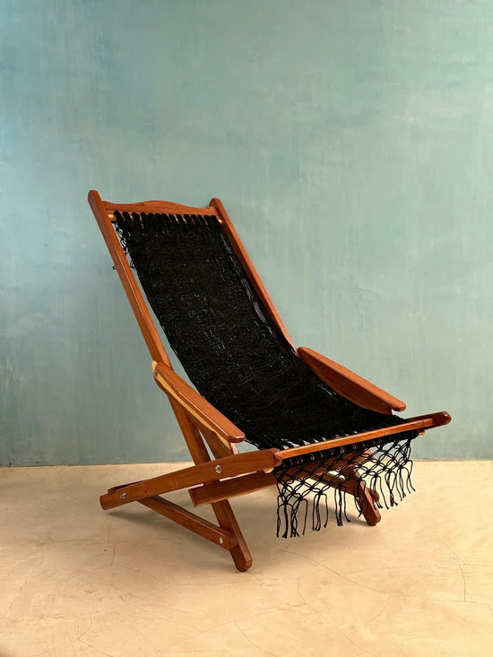 Silla mecedora artesanal plegable de Yucatán color negro abierta, colocada en exterior con vista lateral