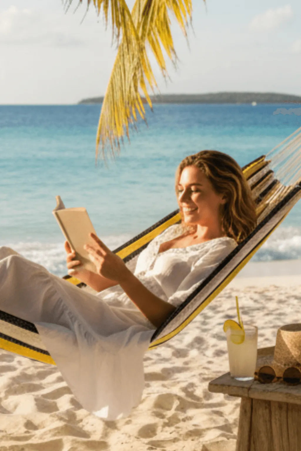 Mujer leyendo en hamaca mexicana artesanal amarilla y beige colgada en playa frente al mar